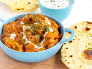 A food photograph of Indian butter chicken and naan bread